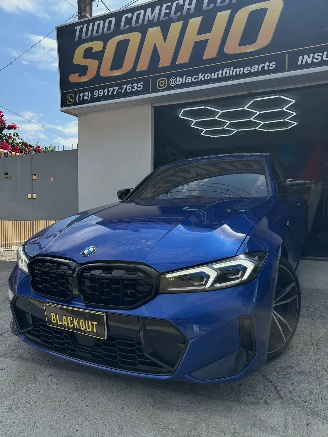 BMW azul sob as luzes hexagonais da loja